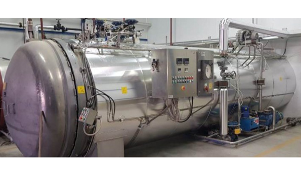 autoclave industrial, un recipiente hermético diseñado para soportar altas presiones y temperaturas elevadas, utilizado comúnmente para esterilizar envases de alimentos como vidrio y metal.